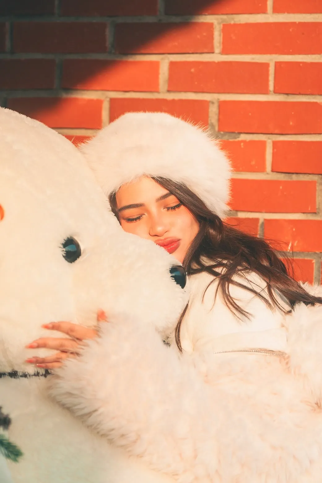 Denise Laurel resting against a giant white teddy bear