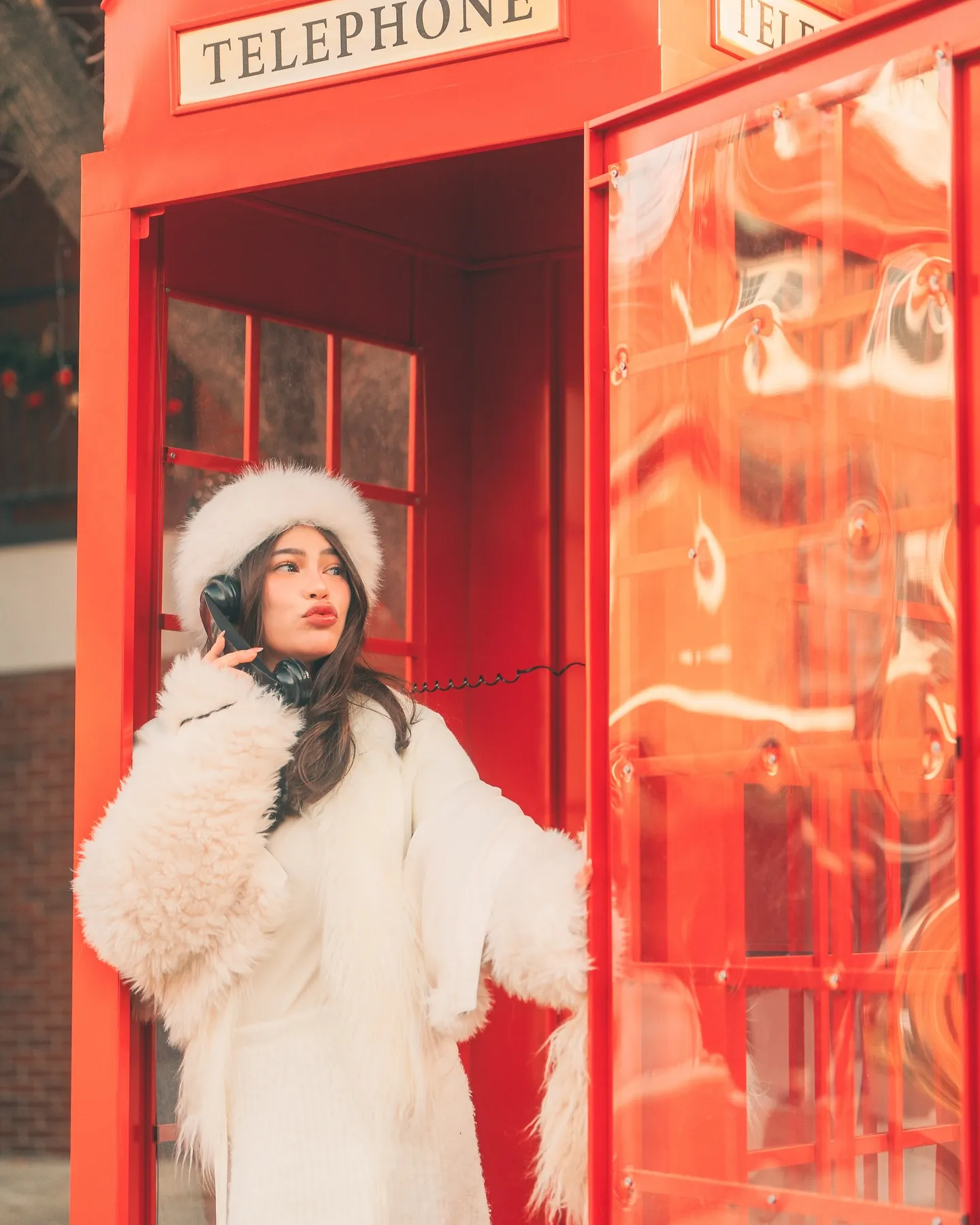 Denise Laurel standing at the door of a red telephone booth