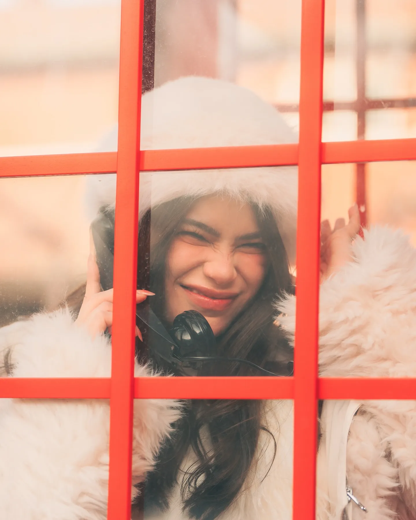 Denise Laurel grinning through the red frame of the booth window