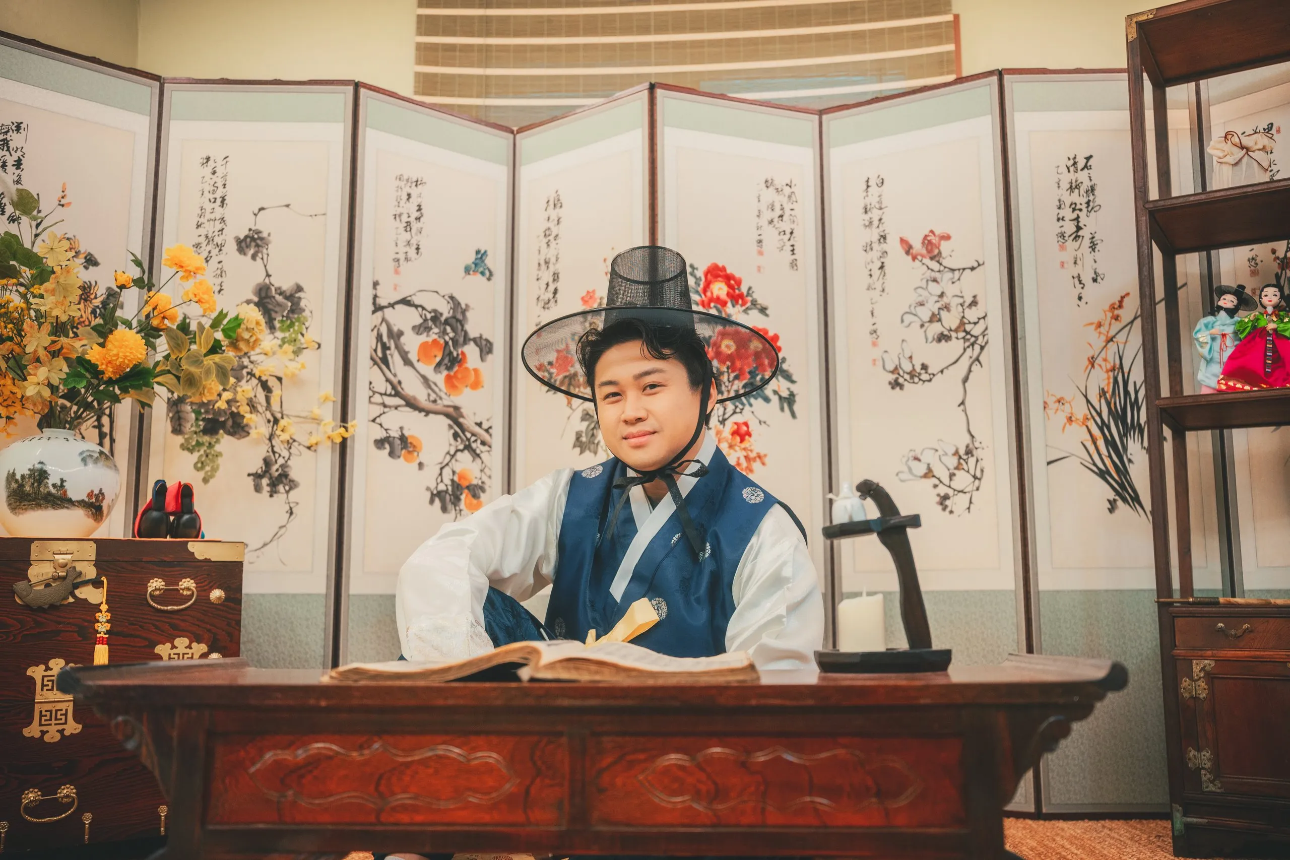 Ivan in hanbok at a writing desk in the folk studio