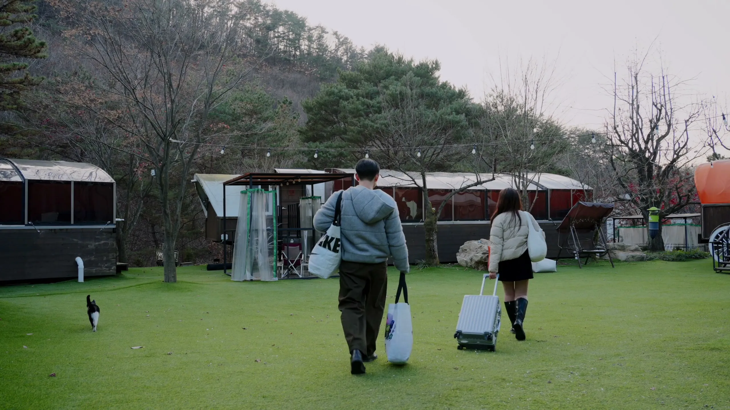The two of them crossing the lawn to their glamping site, bags in hand, on the first evening.