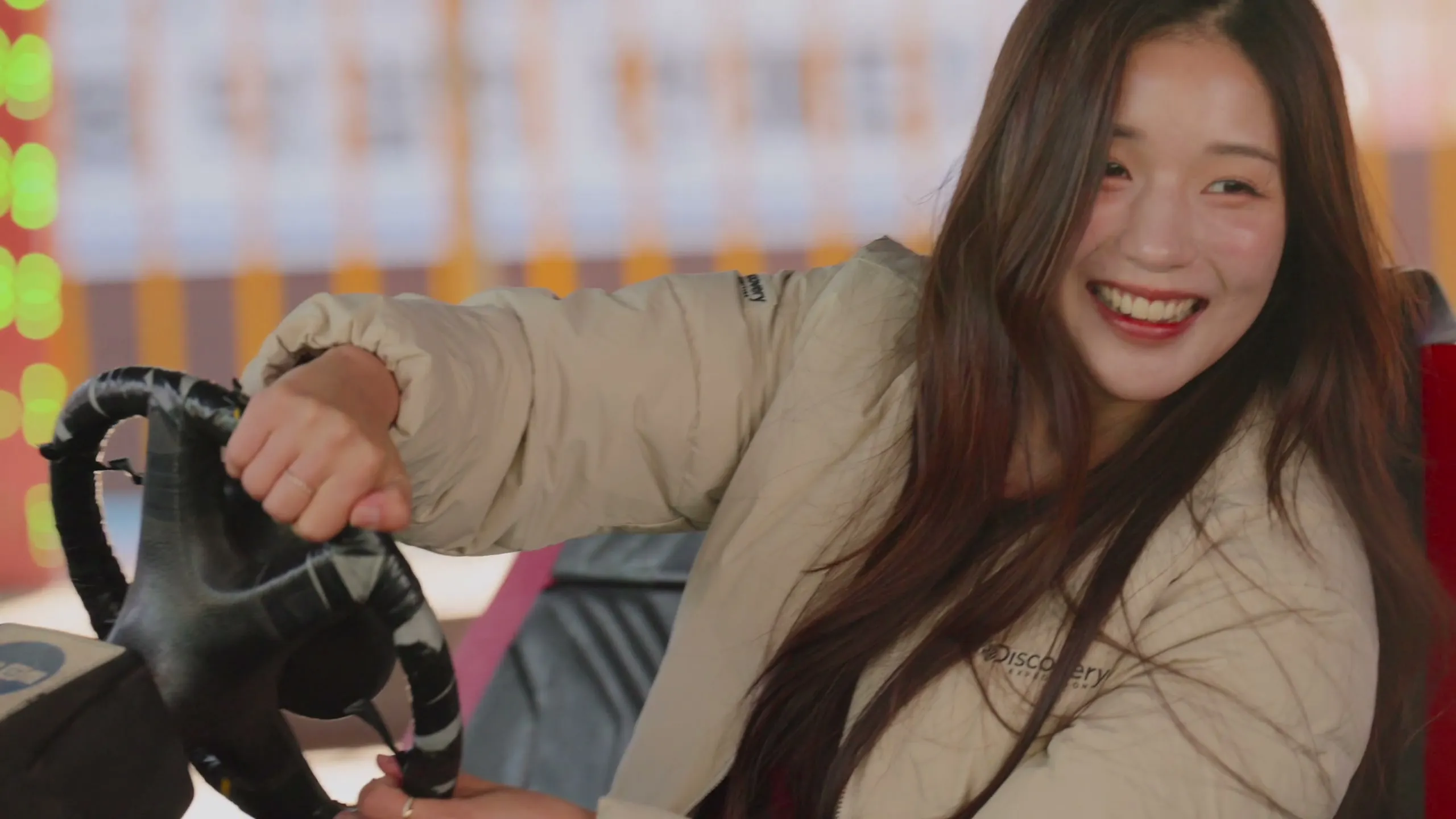 At the amusement park, the bride laughing at the wheel of a bumper car, the groom beside her.