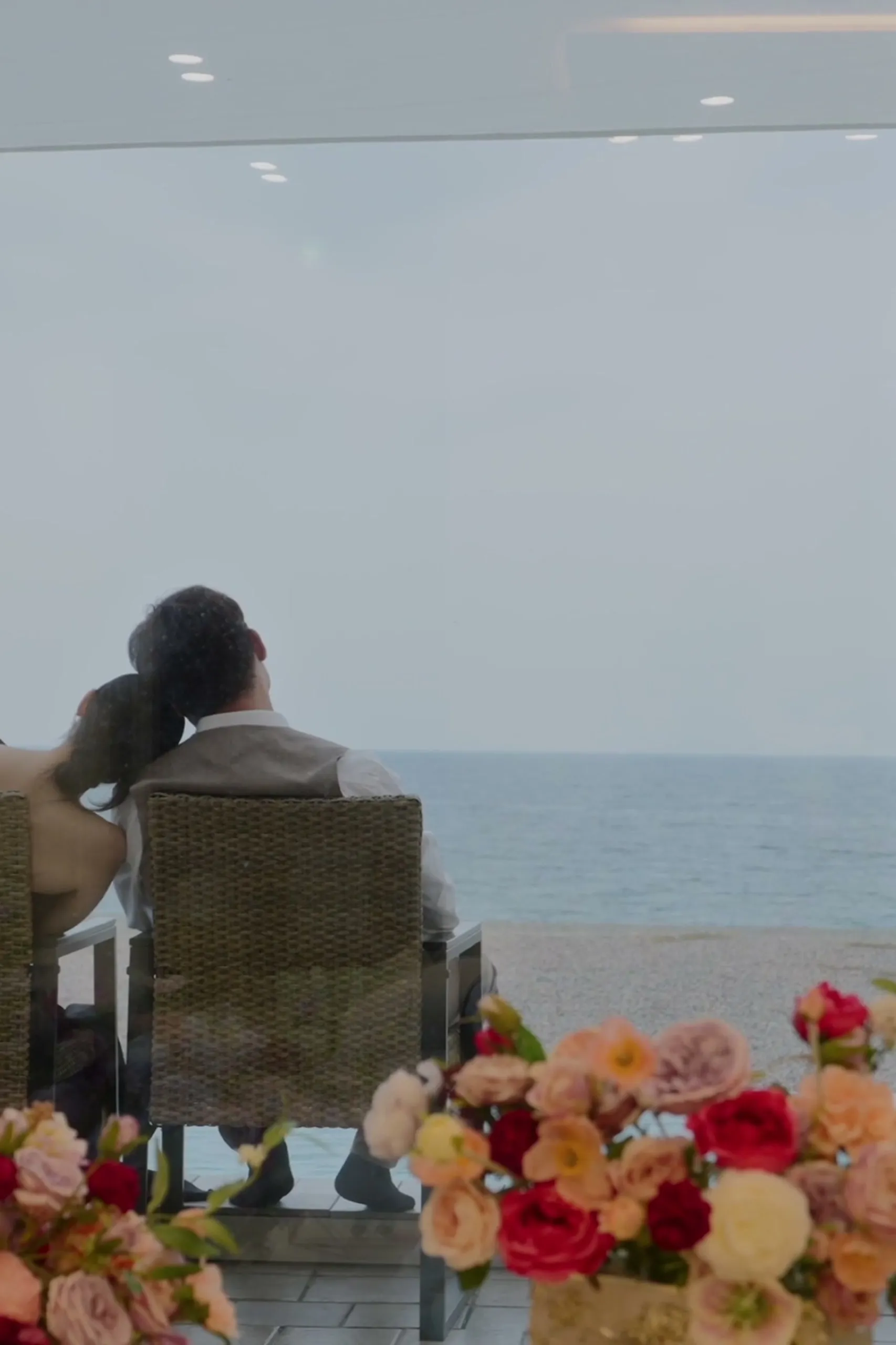 Seen from behind, the two of them seated together, looking out at the sea.