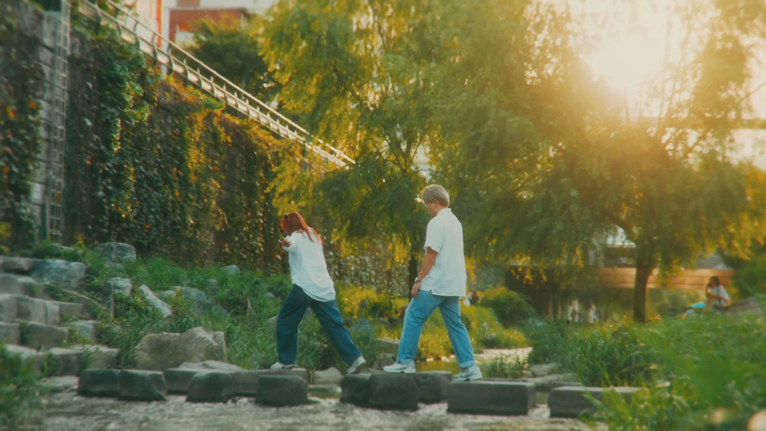 Joshua and Wei Li walking into golden-hour light along Cheonggyecheon.