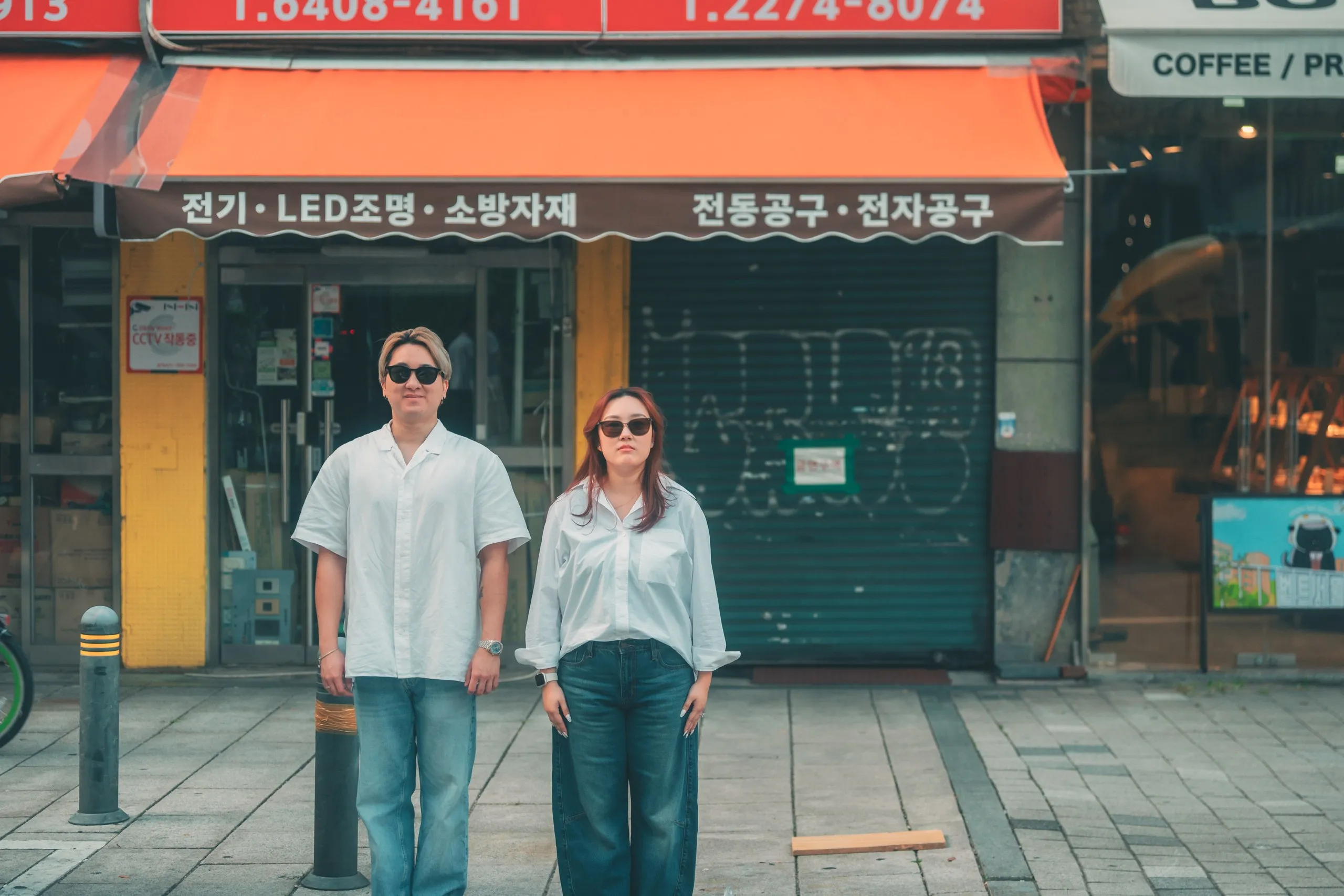 Joshua and Wei Li in matching white shirts and sunglasses on a retro Jongno street