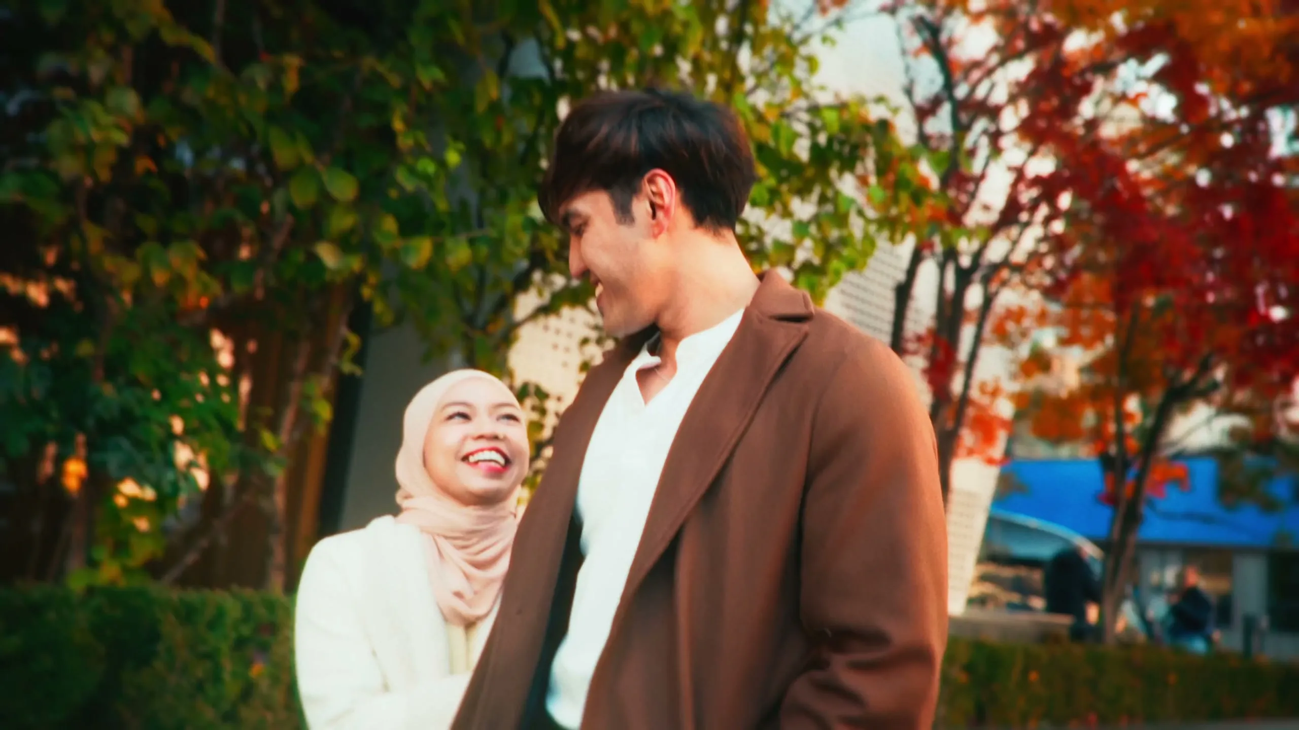 Adila and her partner laughing under autumn trees on a Seoul street