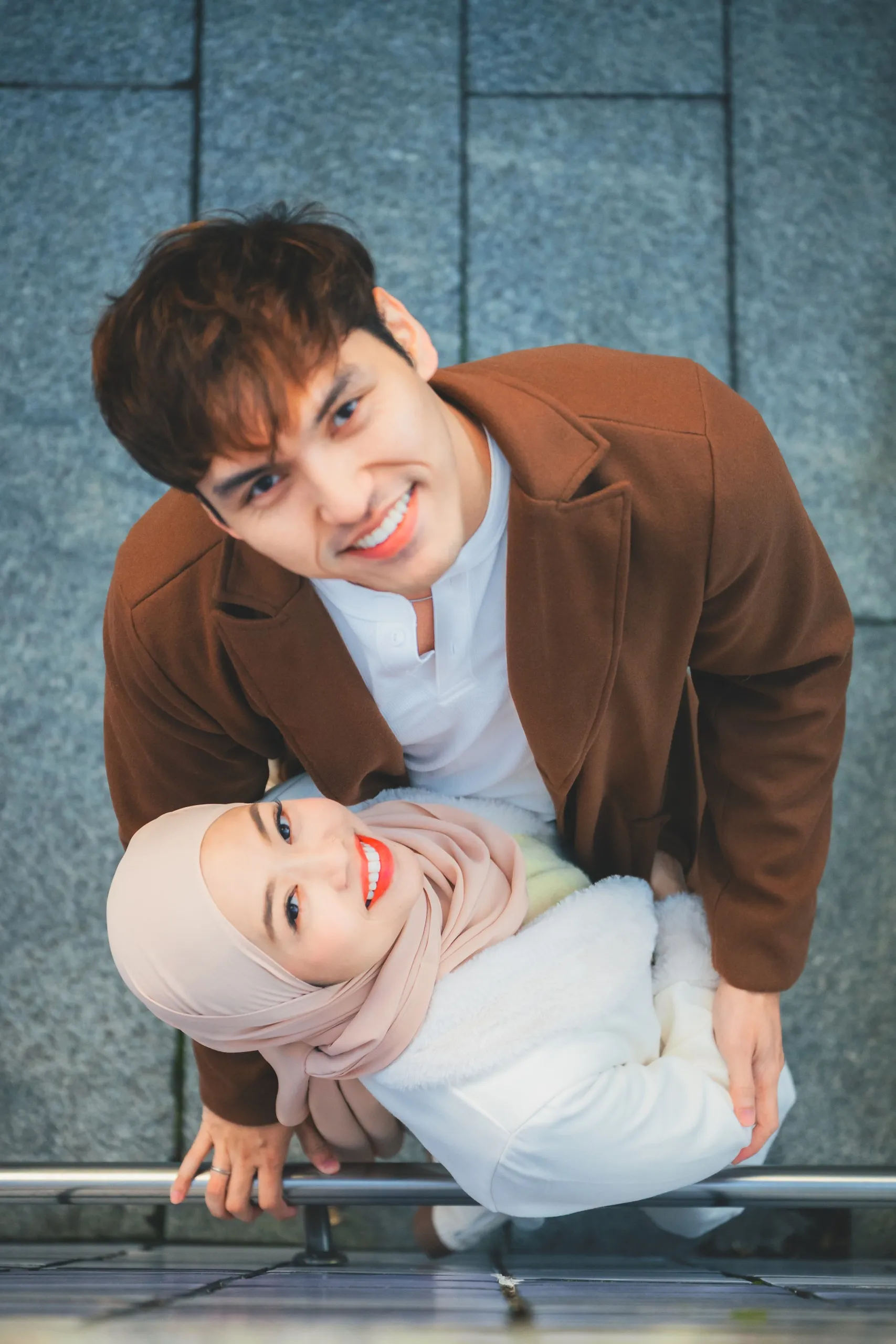 Adila and her partner leaning over a railing, laughing