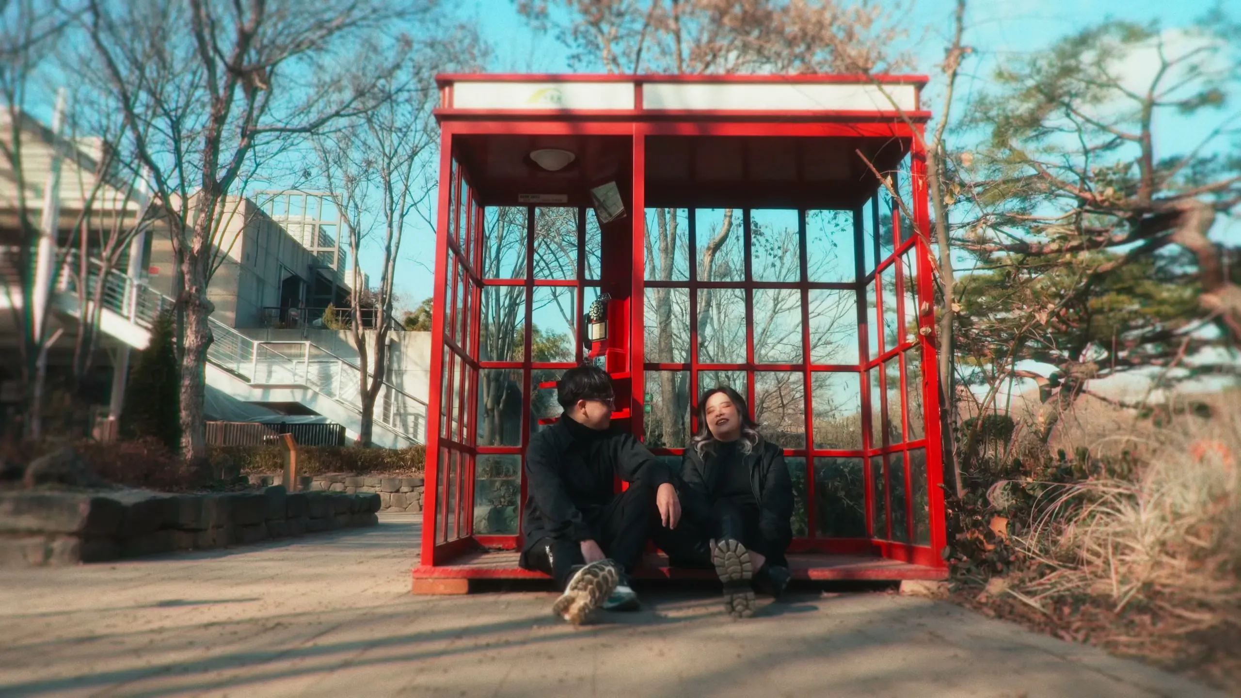 Tracy and her partner crouched together inside a red glass phone booth