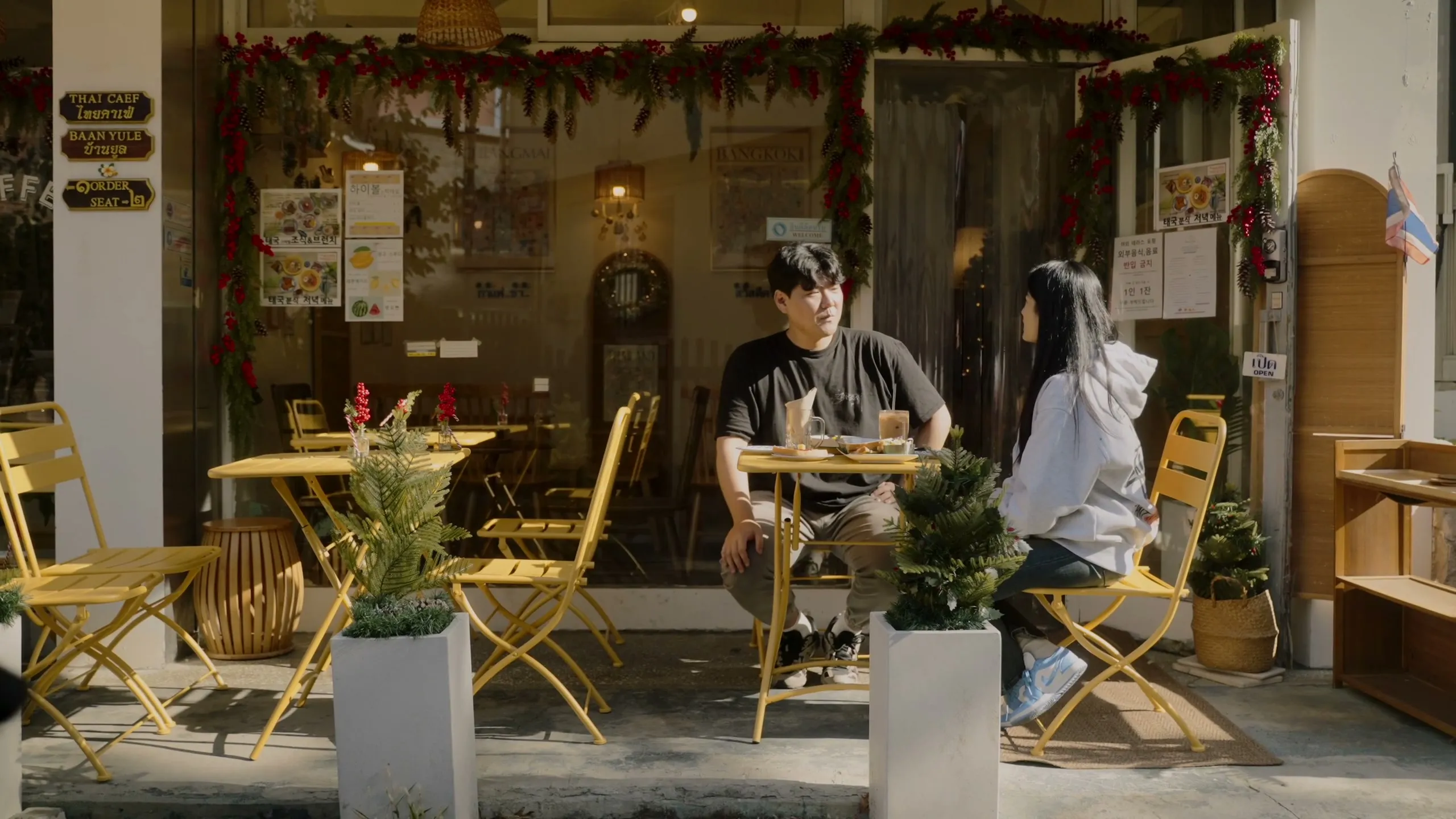 The two seated at an outdoor cafe table on a Haebangchon corner.