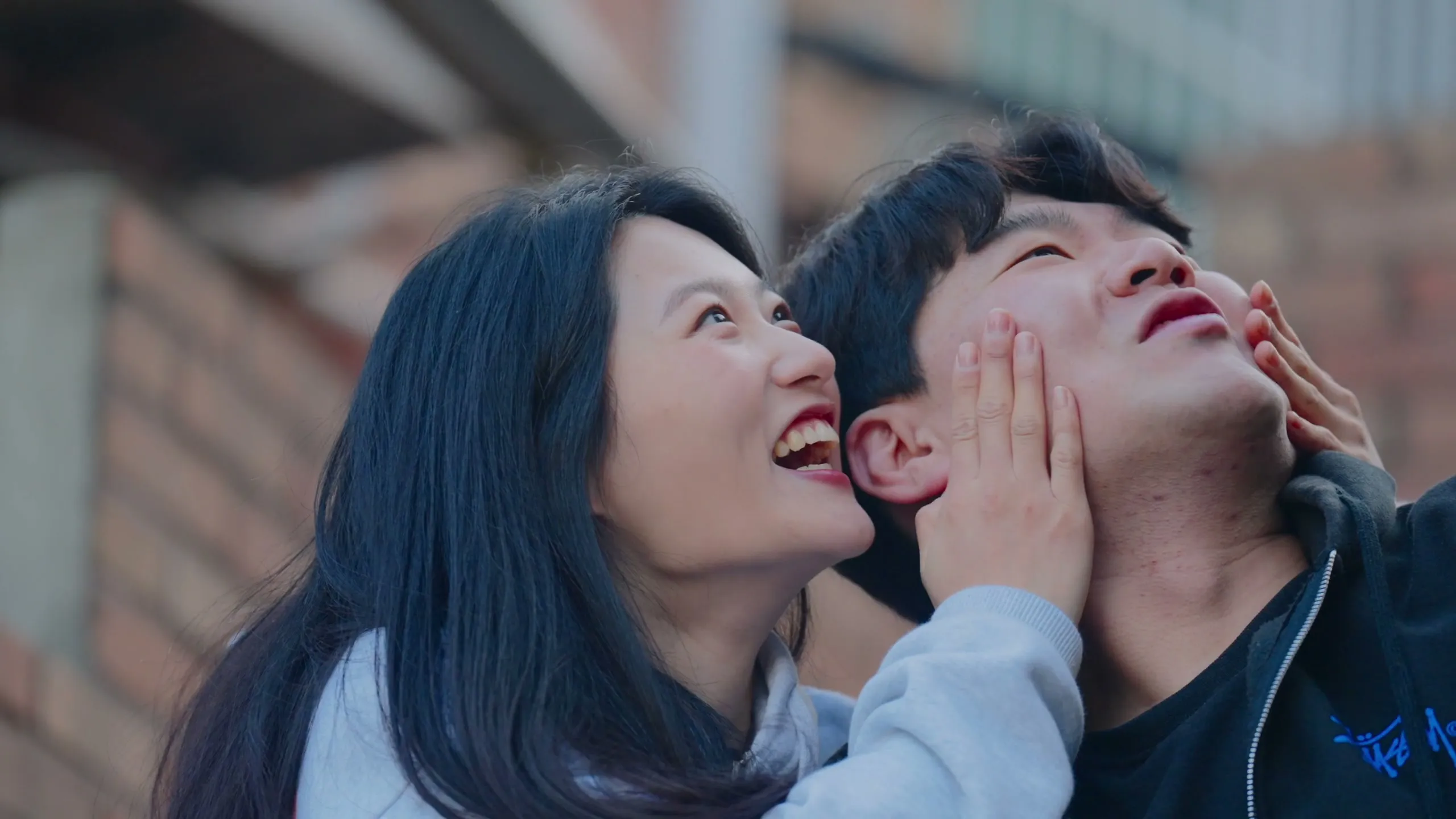 Chaeyeon holding Haeseong's face in both hands as they both laugh on a Haebangchon staircase.